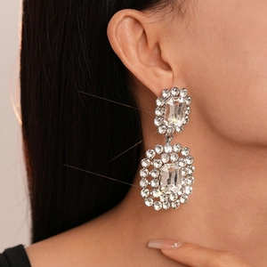Close-up of luxury geometric silver earrings with sparkling crystals worn by a model