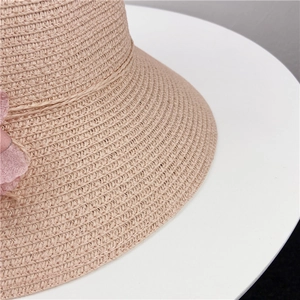 Detailed close-up of straw sun hat featuring a delicate fabric flower and woven texture
