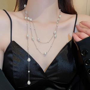Detail view of a triple-layered necklace with irregular baroque pearls on a black dress