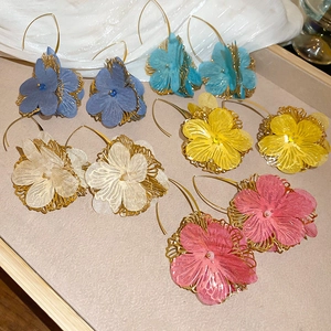Détail de boucles d'oreilles fleuries avec pétales en tissu translucide et fil d'or