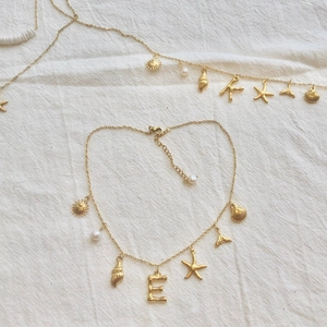 Detail of golden stainless steel necklace with ocean charms star shell and pearl