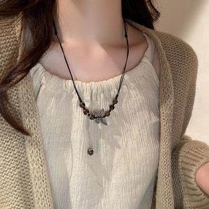 Detail of beaded ethnic necklace featuring a silver butterfly pendant and woven cord
