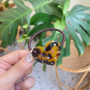 Detail of high-elastic hair tie with heart tortoiseshell pendant and colorful rhinestones