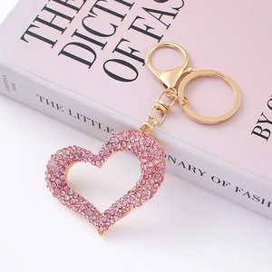 Detailed close-up of a pink crystal heart keychain with a golden lobster clasp on a book