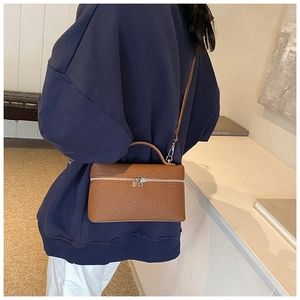 Back view of model styling a brown lychee pattern leather box handbag with silver zipper