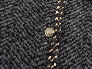 Detail of tweed knit jacket with gold crown button and sequin trim finish