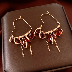 Detail of 18K gold-plated heart earrings with red crystal beads and metal tassels