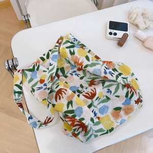 Detailed close-up of colorful floral cotton tote bag with wide handles on a white table