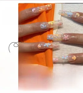 Dettaglio di unghie finte floreali con piccoli fiori colorati e perle bianche