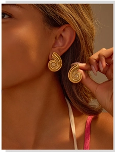 Close-up of gold spiral seashell earrings with 18K gold plating on model's ear