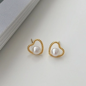 Detailed close-up of heart-shaped pearl earrings with twisted gold borders on a white base