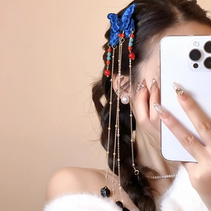 Détail d'une pince à cheveux papillon bleu avec de longs glands et perles colorées