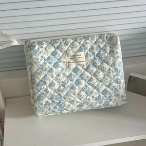 Detail of blue floral quilted makeup bag featuring zipper and ribbon puller detail