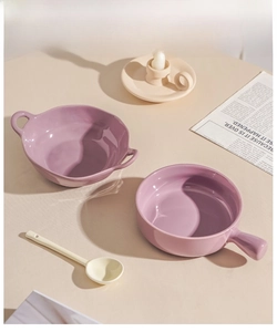 Detail of lavender ceramic bowls with handles and matching spoon on a warm wooden table