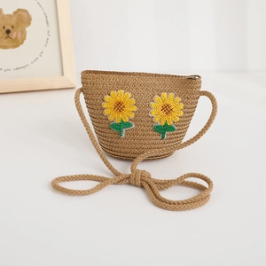 Dettaglio di una borsa a tracolla in paglia per bambini con due ricami di girasoli