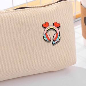 Pink heart gaming headphones enamel pin on a beige canvas bag for cute accessory styling