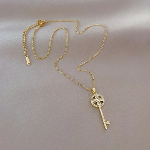 Golden titanium steel key necklace with luxury crystals on elegant grey silk backdrop