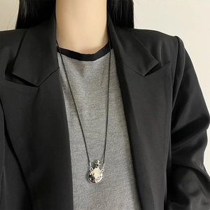 Silver perfume bottle pendant necklace styled on a black blazer for a minimalist look