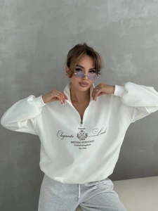 Detail of white quarter-zip sweatshirt featuring British Heritage print and crown crest