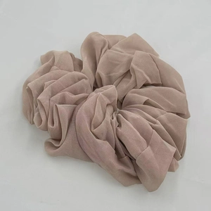 Close-up of light brown chiffon scrunchie with soft pleated fabric texture details