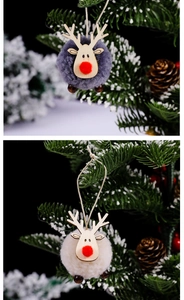Detail of gray and white felt reindeer ornaments with wooden antlers on Christmas tree