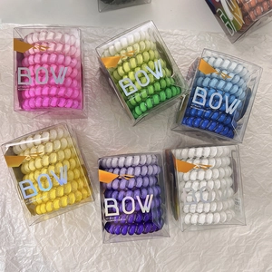 Detail view of colorful gradient spiral hair ties in transparent storage boxes