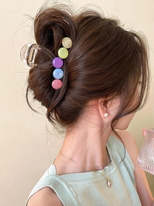 Detail view of a clear acrylic claw clip with colorful round beads on a woman's updo hairstyle