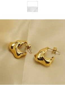 Detail of gold-plated irregular lava textured titanium steel earrings on silk