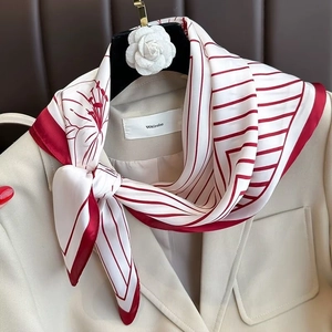 Elegant red and white striped silk scarf with floral patterns tied on a beige suit