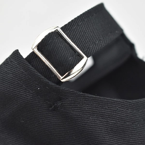 Detailed macro view of the adjustable metal buckle and cotton fabric on a black baseball cap