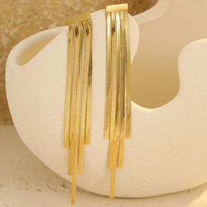 Detailed view of gold tassel earrings hanging on ceramic vase with soft lighting
