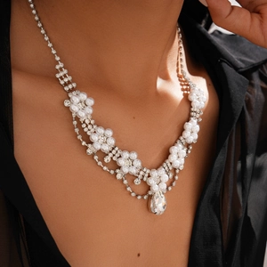 Detail shot of pearl flower necklace featuring a crystal teardrop pendant on a model