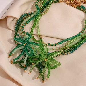 Detailed close-up of green crystal beaded layers and golden flower pendant charms