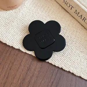 Elegant black resin flower hair clip with wer letters on textured linen background