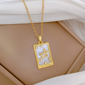 Close-up of golden tarot card pendant with star and moon charms on luxury silk