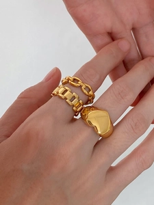 Detail shot of three gold vintage rings in chain, gear, and heart shapes on a model hand