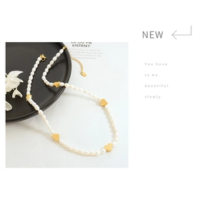 Detailed macro view of white freshwater pearls and golden heart charms on a choker necklace