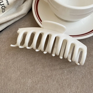 Detailed view of a white minimalist square hair claw clip on soft brown suede fabric