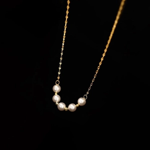 Elegant gold titanium necklace with alternating white pearls and gold beads on a black background