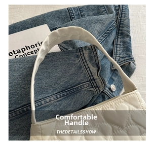 Détail d'un sac à main blanc avec surpiqûres en cœur sur un fond en denim foncé