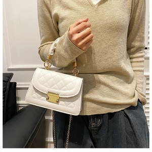 Primer plano de bolso bandolera blanco acolchado con cadena dorada usado por una modelo