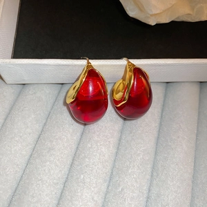 Macro detail of red teardrop resin earrings with irregular gold-plated metallic edges
