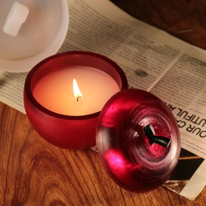 Vue détaillée d'une bougie rouge en forme de pomme allumée sur un bureau en bois vintage