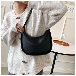 Sac à bandoulière en forme de croissant en cuir noir lisse porté par un mannequin avec style