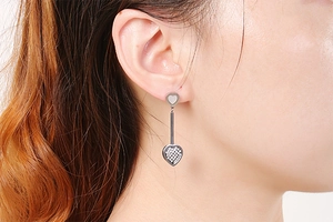 Close-up of silver long heart earrings with rhinestones on model with white background