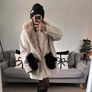 Eleganter beiger Wollmantel mit großem Kunstpelzkragen und schwarzer Strickmütze für Winter