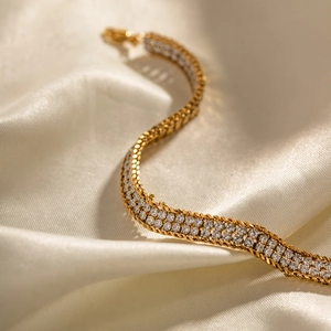 Detail of three-row white zircon micro-pave gold bracelet on elegant cream satin fabric
