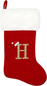 Detail of red velvet Christmas stocking with white plush trim and golden glitter letter H