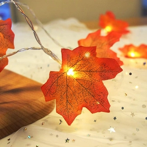 Fall maple leaf LED string lights with warm glow on wooden background for home decor