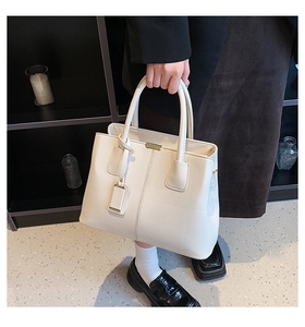 Close-up of cream white lychee leather handbag with golden hardware and double handles